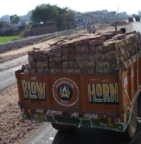 Sign on truck loaded with bricks read, "Blow horn".