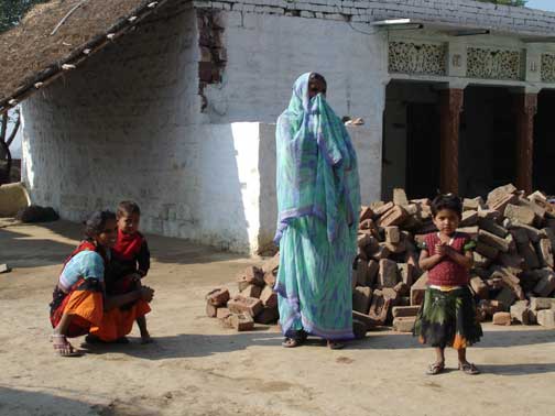 Women and small children in front of their home.