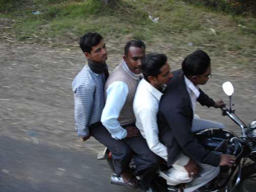 Four men riding a motor scooter.